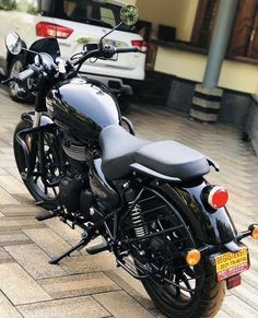 a black motorcycle parked next to a white car