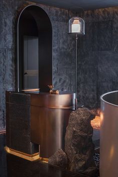 a bathroom with a large round tub next to a stone wall and flooring area