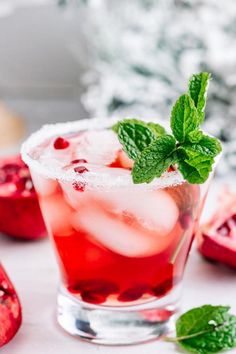 a pomegranate and mint cocktail garnished with fresh mint on a white surface