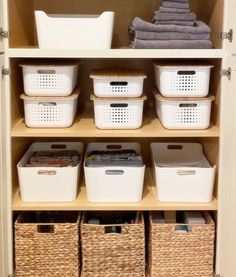 an organized closet with baskets and towels on the shelves, including bins for laundry