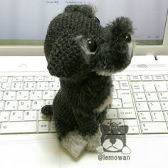 a small stuffed animal sitting on top of a laptop computer keyboard, in front of a monitor