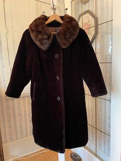 "This elegant coat is made from \"Borglaska, A Borg Fabric,\" or faux mouton fur, in deep, rich brown, with a silky mink fur collar in the same deep brown tones. The coat has the original decorative buttons in the front and two front pockets, and is fully lined with dark brown satiny lining. Sold by Pearlman's Ladies Wear in Regina, Saskatchewan (where we live!). The measurements, taken with the coat lying flat, are: shoulder to shoulder, 18 inches; armpit to armpit, 21 inches; sleeves, 23 inches; length, 43 inches; bottom edge, 30 inches. In very good condition." Brown Winter Fur Coat For Formal Occasions, Brown Fur Coat For Formal Winter Occasions, Brown Long Coat With Faux Fur Trim, Regina Saskatchewan, Elegant Coats, Ladies Wear, Coat Winter, Brown Tones, Brown Coat