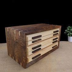 a wooden box sitting on top of a table next to a potted plant