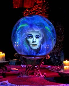 a woman with blue hair is surrounded by candles