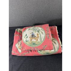 a pink and green pillow with a camel on it's side sitting on a couch