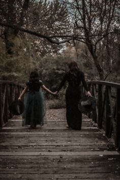 two women walking across a bridge holding hands