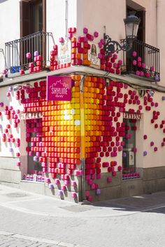 a building covered in pink, yellow and orange cubes next to a street light