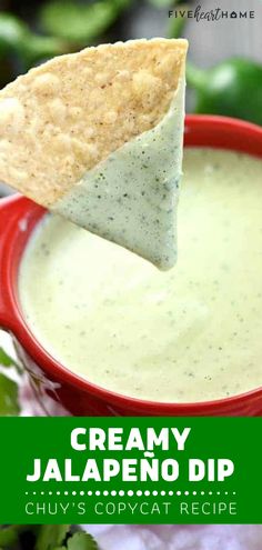 a tortilla chip being dipped into a bowl of creamy jalapeno dip