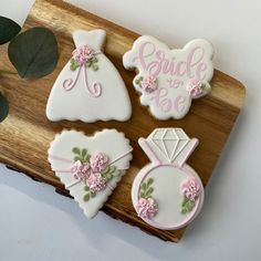 three decorated cookies sitting on top of a cutting board next to a plant and some leaves