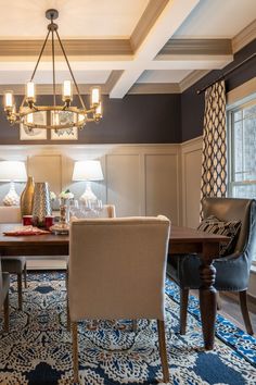 a dining room with blue and white rugs, chandelier and table in the middle