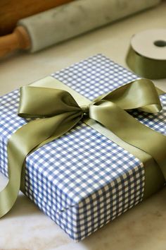 a blue and white checkered gift box with a green ribbon on it next to a roll of toilet paper