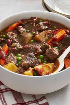 a white bowl filled with beef stew and potatoes