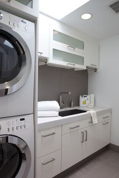 a washer and dryer in a small room with white cabinets on the walls