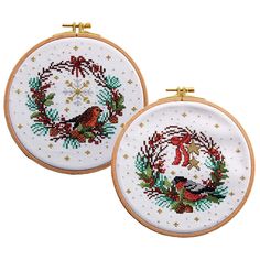 two cross stitch hoops decorated with christmas wreath and birds on white background, one has gold trim