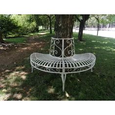 a white metal bench sitting under a tree