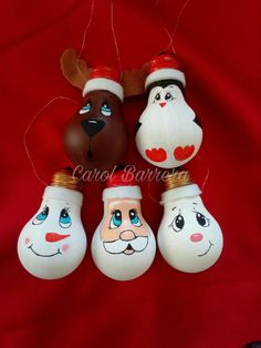 four blown glass christmas ornaments hanging on a red cloth with santa claus, snowman and reindeer faces