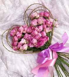 pink roses are arranged in a heart - shaped arrangement on a white lace tablecloth