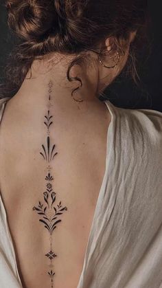 the back of a woman's neck with an intricate tattoo design on her left side