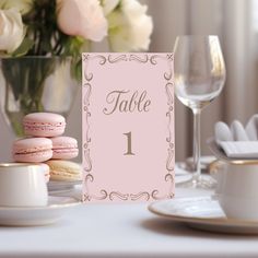 a table setting with pink macaroons and wine glasses