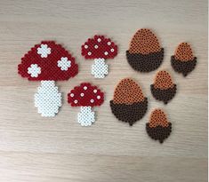 several pieces of perler bead art are arranged on a wooden surface, including mushrooms