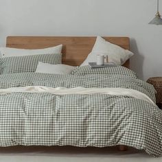 an unmade bed with pillows and blankets on the headboard, next to a lamp