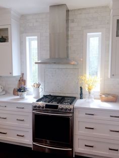 a stove top oven sitting inside of a kitchen next to white cabinets and counter tops