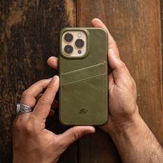 a person holding an iphone case with a card holder in their hand on a wooden surface