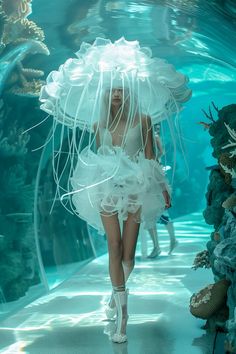 a woman walking down a runway in a white dress