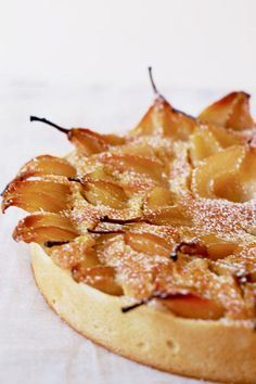 an apple tart with powdered sugar on top sitting on a white tablecloth