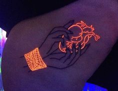 a neon tattoo on the back of a woman's arm with an orange glow