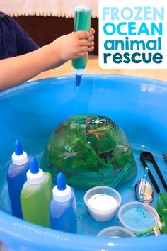 a child is playing in a blue tub filled with water and other items to make an ocean animal rescue