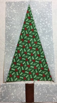 a green and red christmas tree sitting on top of a piece of paper in front of a white wall