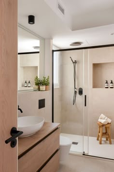 a bathroom with a sink, toilet and shower in it's corner area next to a wooden stool