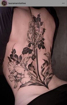 a woman's lower back tattoo with flowers and leaves on her stomach, in black and white