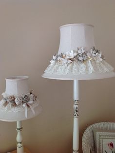 two white lamps with flowers on them sitting next to each other