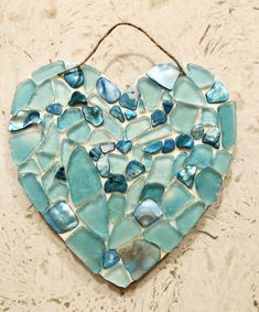 a heart shaped glass mosaic hanging on a wall in the shape of a sea foam