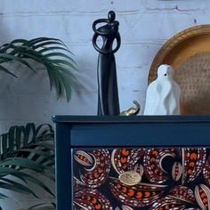 an artistically designed wooden box sitting on top of a table next to a potted plant