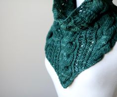 a green knitted scarf on top of a white mannequin