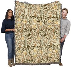 a man and woman are holding up a large quilt that has been made to look like an intricate floral pattern