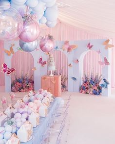 there is a cake and balloons on the table in this room with pink curtains, blue walls, and white flooring