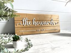 a wooden sign that says the howards on it next to some succulent plants