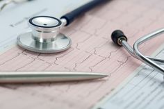 a stethoscope laying on top of a medical paper next to a pen