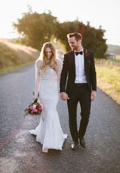 a bride and groom are walking down the road together in their tuxedo attire