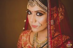 a woman in a red and gold bridal outfit, with her nose ring on