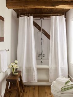 a bathroom with a white bathtub and wooden flooring, along with two towels hanging on the wall