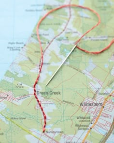 a map with a needle on top of it next to a red string and thread