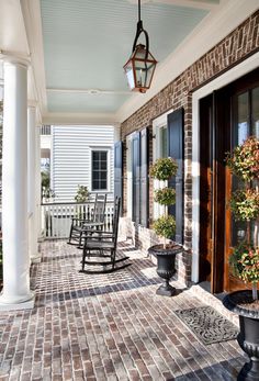 a porch with rocking chairs and potted plants