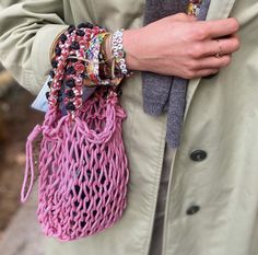 a close up of a person holding a pink bag with bracelets and rings on it