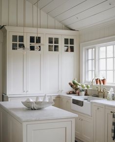 a kitchen filled with lots of white cabinets and counter top space next to a window