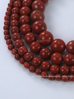 three strands of red wood beads on a white surface